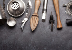 Essential bar tools for home bartenders, including shaker, jigger, and strainer
