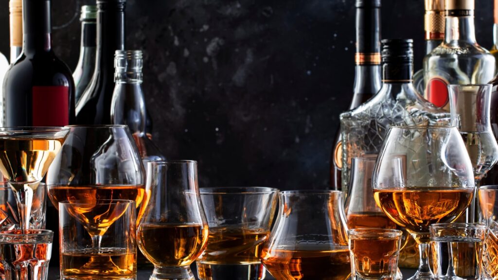An array of spirits and glassware set against a dark background — showcasing a well-stocked home bar setup.