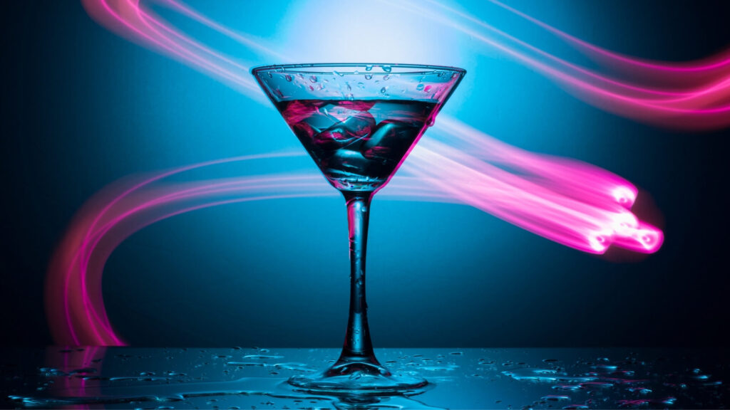 Martini glass with ice under dramatic blue and pink neon lights