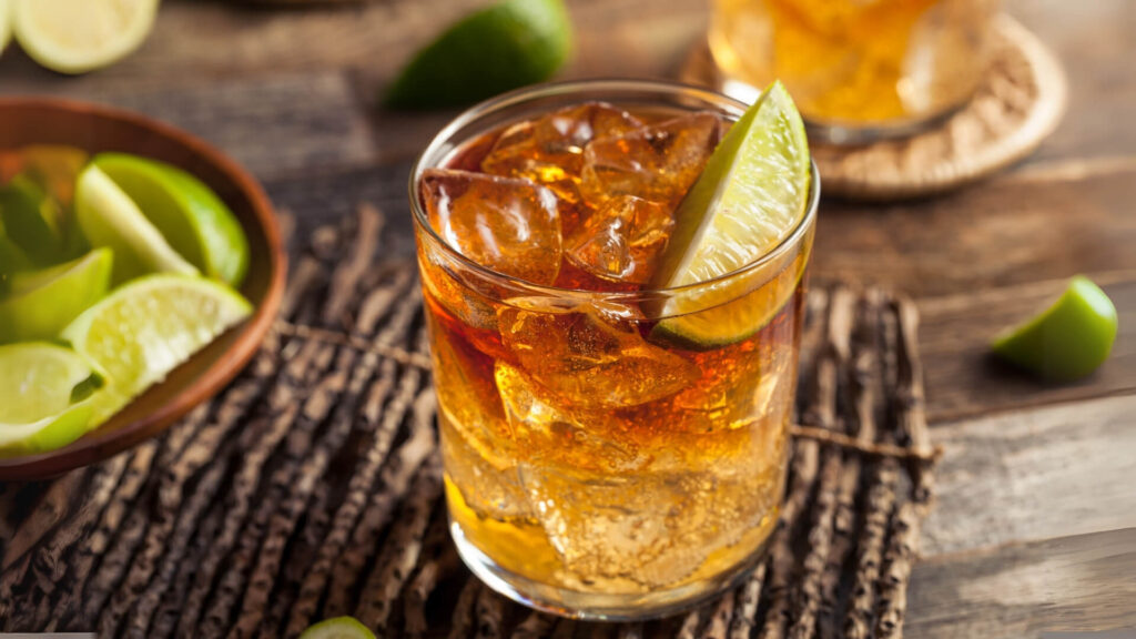 Rum cocktail served on the rocks in a lowball glass with a lime wedge garnish.